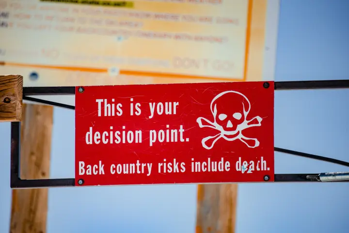 White skull and lettering on a red background: “This is your decision point. Back country risks include death.”