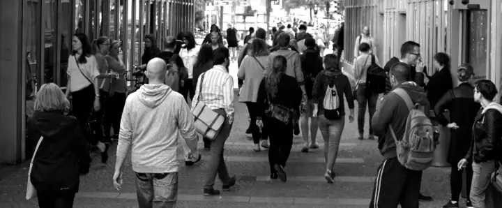 Black and white photo of numerous people on a sidewalk.