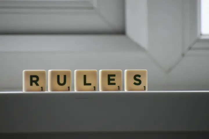 Scrabble tiles sitting on a ledge that spell:  RULES.