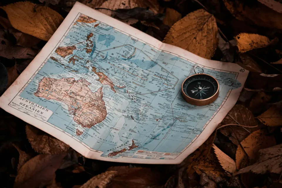 A map showing Australia, New Zealand, and Indonesia on a bed of leaves, held down with a compass.