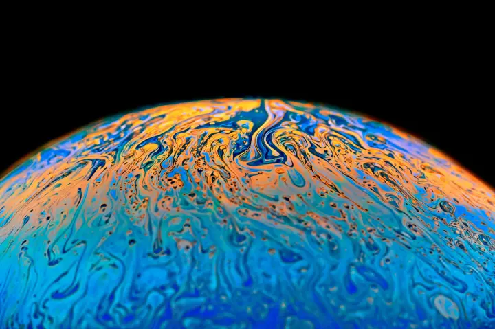 Top half of a globe covered with flowing blue and orange colors against a black background.